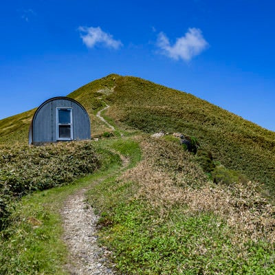 避難小屋と山頂へと続く登山道（谷川岳）の写真