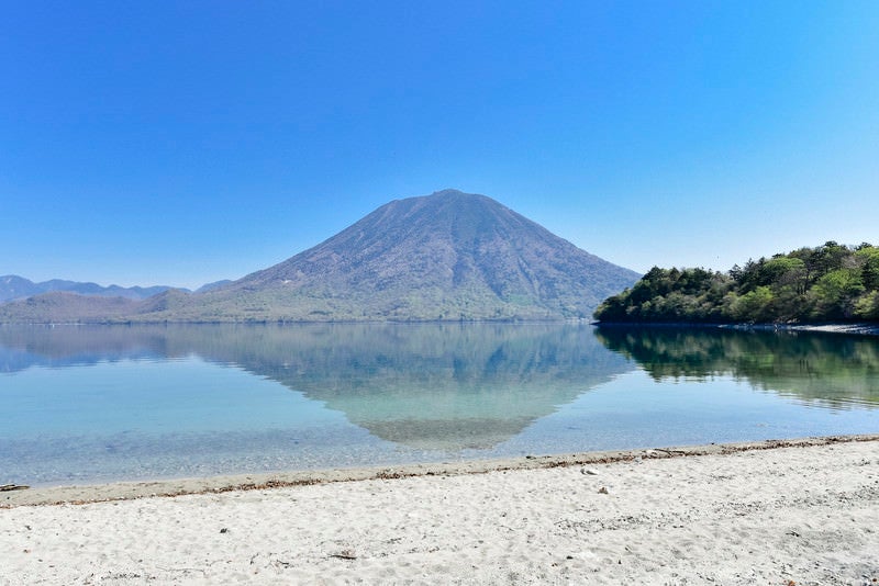 砂浜の向こうに浮かぶ男体山（栃木県日光市）の写真