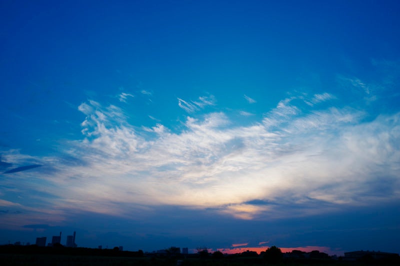 さいたま新都心の向こうへと沈んでいく夕日と雲の青空の写真