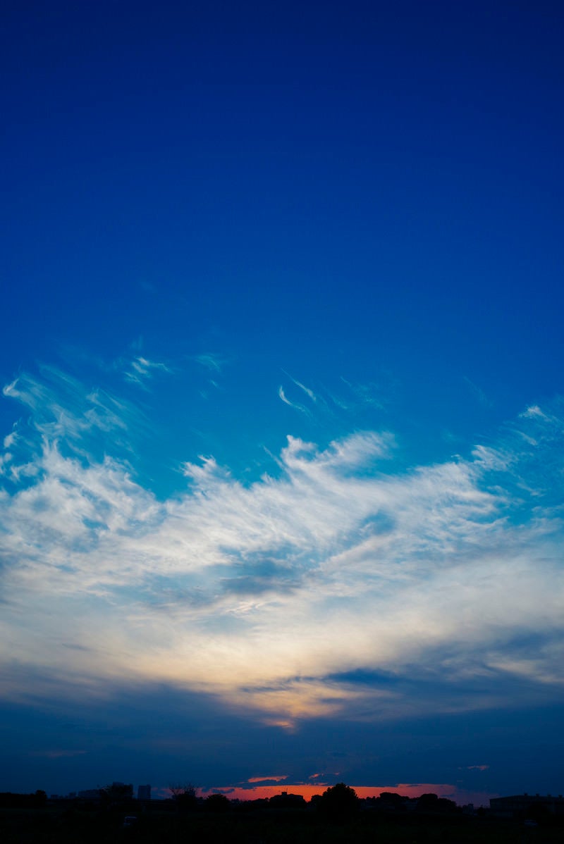 真っ青な空に広がる雲と夕日の写真