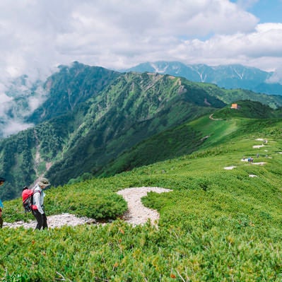 爺ヶ岳から種池に下る登山者と北アルプス北部の山々の写真