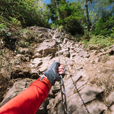 行者返しの鎖を握る登山者の写真