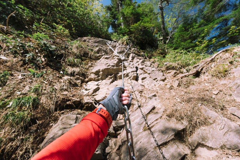 行者返しの鎖を握る登山者の写真