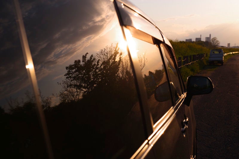 車窓に映る夕日と木々の姿の写真