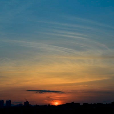 空を水色とオレンジに染める夕日の写真