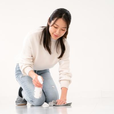 シュッシュと床に洗剤を噴きかける女性の写真