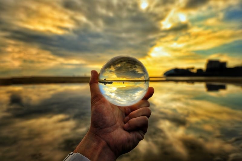 ガラス玉の中の夕焼けと浜辺の写真