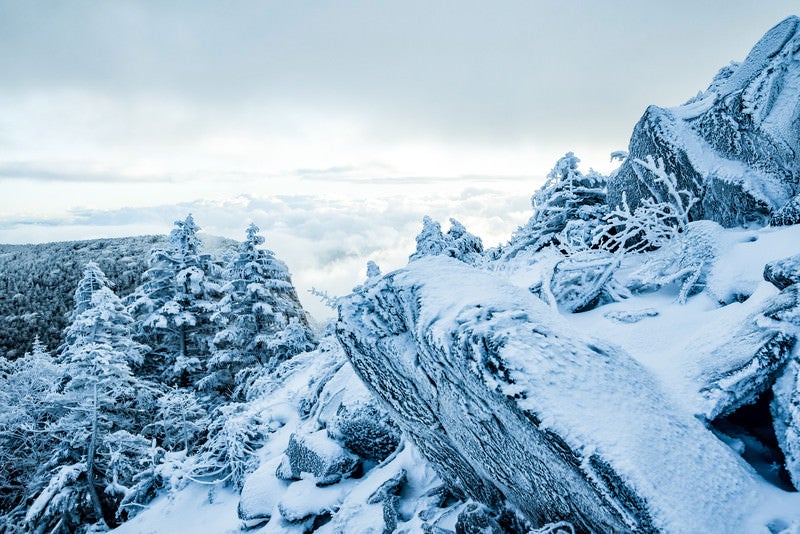 凍り付く山肌と眼下に広がる雲の写真