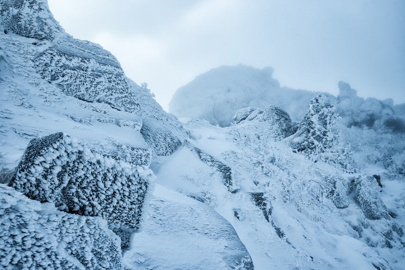 立ち込めるガスで視界不良の雪山の写真