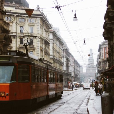 ミラノの時計台へと続く路地を走る路面電車と街並み（イタリア）の写真