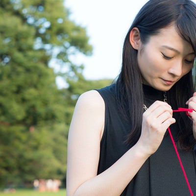 ちぎれた赤い糸を結び直す女性の写真