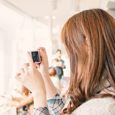 デジカメを持って撮影する女性の写真