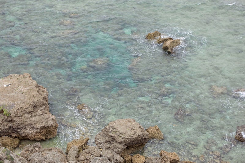 ゴツゴツした岩場と透き通る海の写真