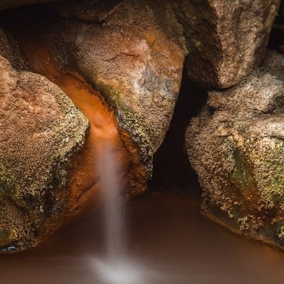 強い温泉成分が固まっている源泉かけ流しの湯出し口の写真