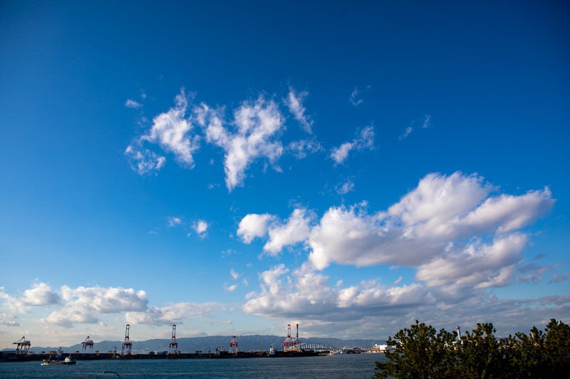 青空に浮かぶ雲とコンビナートの写真