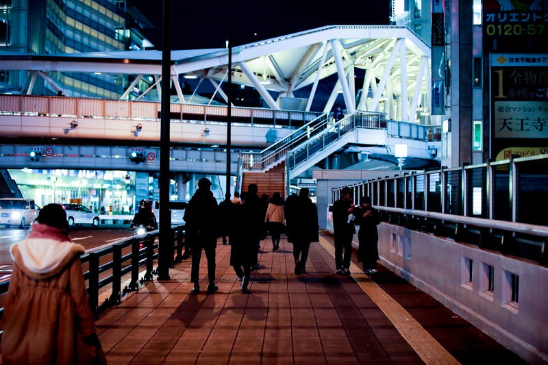 夜の歩道を行き交う人の写真