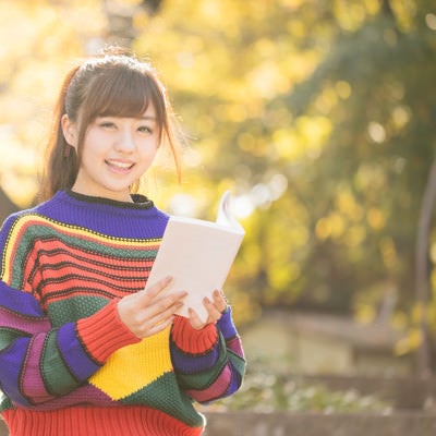 読書の秋、紅葉に包まれる80s風女子の写真