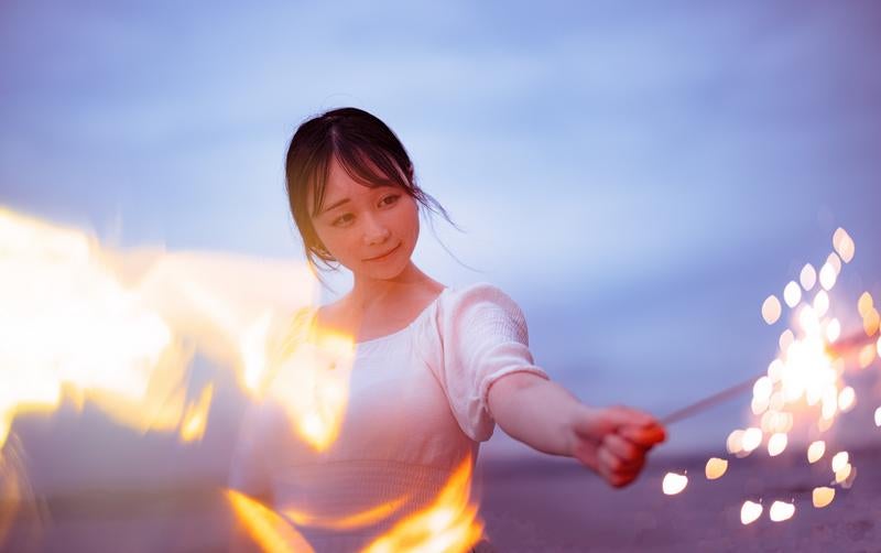 夏の思い出を灯す手持ち花火を楽しむ女性の写真