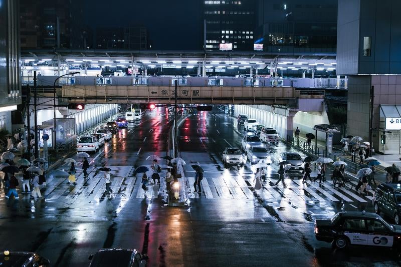 雨上がりの錦糸町駅前横断歩道を歩く人々の写真