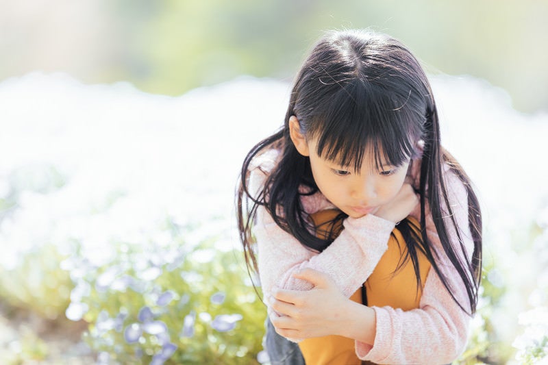 お花畑でうつむく女の子の写真