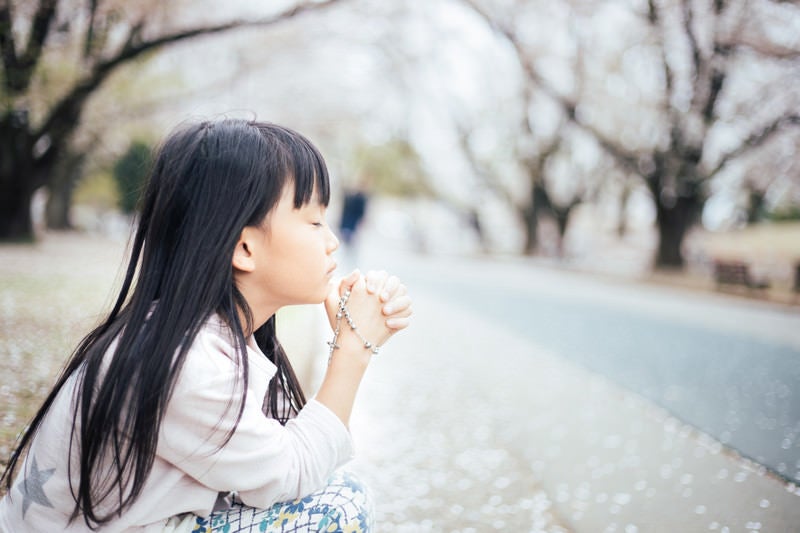 ロザリアを握り締めて願う女の子の写真