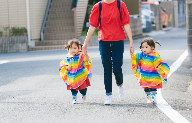 ママと手をつなぐ双子の女児の写真