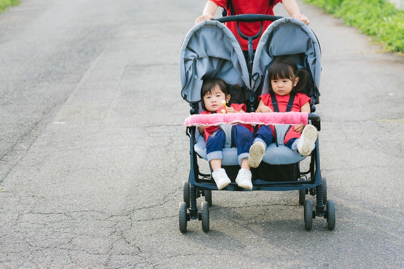 二人乗りベビーカーに乗った双子の姉妹の写真