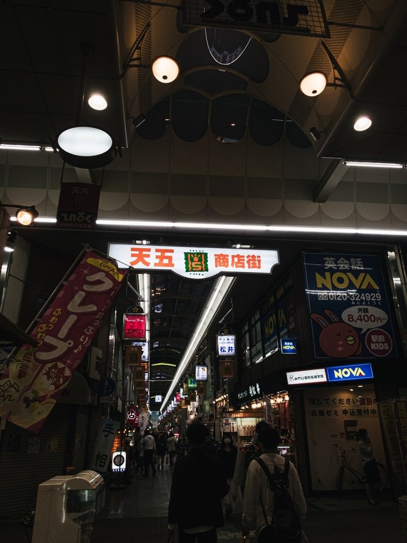 商店街入り口の大きな看板と行き交う人の写真