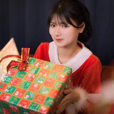 クリスマスにプレゼントを手渡しする女性サンタの写真