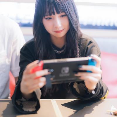 彼氏と一緒に携帯ゲーム機をプレイする女性の写真