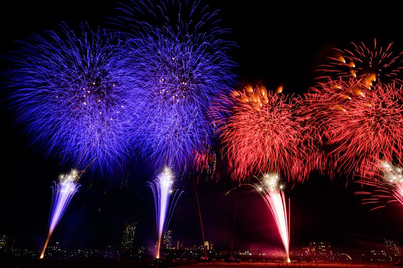 青と赤に別れて打ち上げる花火の写真