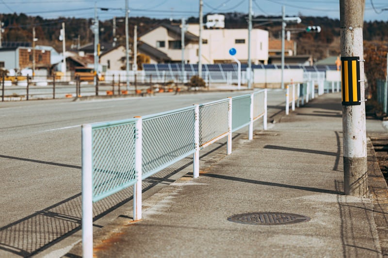 小高のフェンスがある歩道と街並みの写真