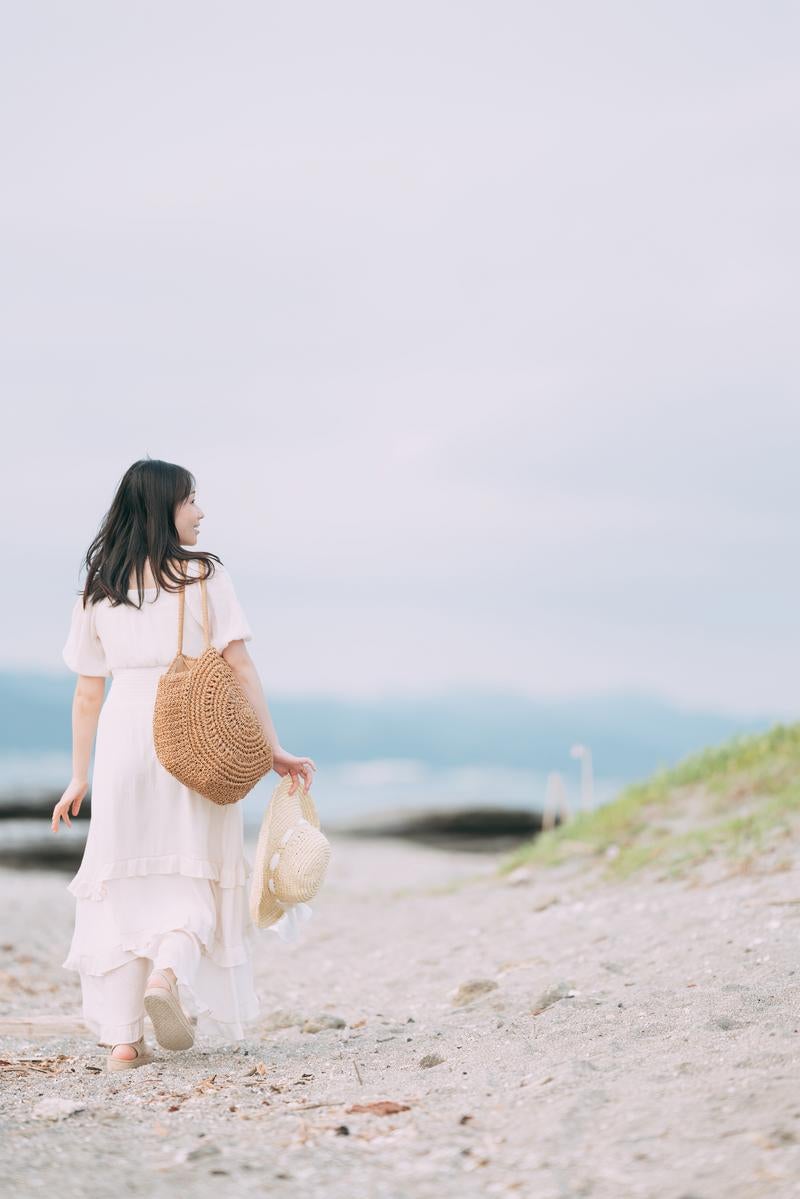 海岸沿いを歩く後ろ彼女の後ろ姿の写真