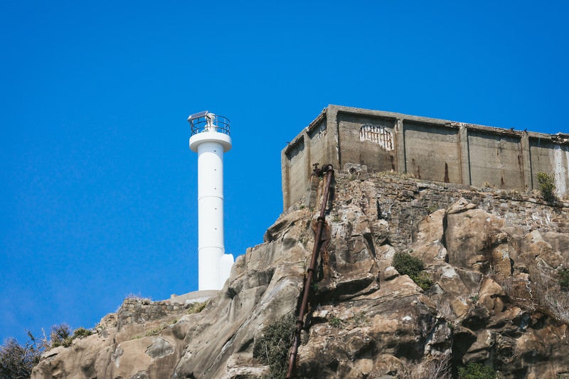 貯水槽と並ぶ肥前端島灯台（軍艦島）の写真