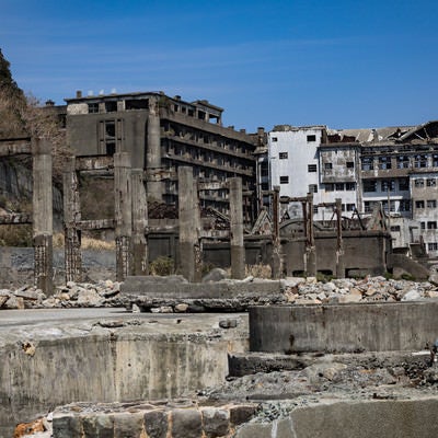 貯炭場越しの端島保育園跡と70号棟小中学校跡（軍艦島）の写真