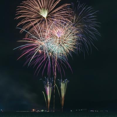 田んぼの真ん中から打ち上がる花火大会の尺玉の写真