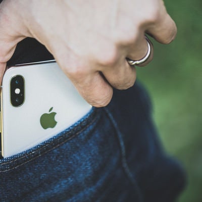 ポケットから iPhone X を取り出す男性の手の写真