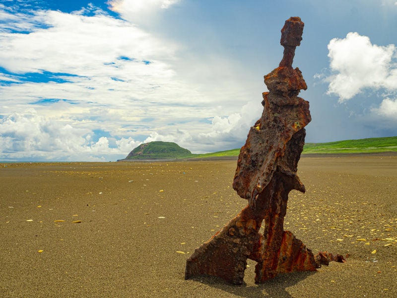 翁浜の沈船の舵部より摺鉢山を望むの写真