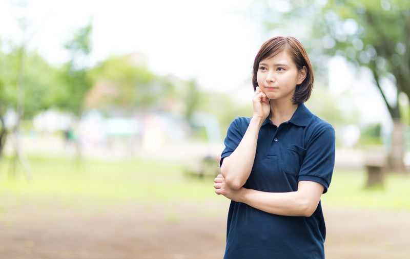 屋外で考え込むヘルパーの女性の写真