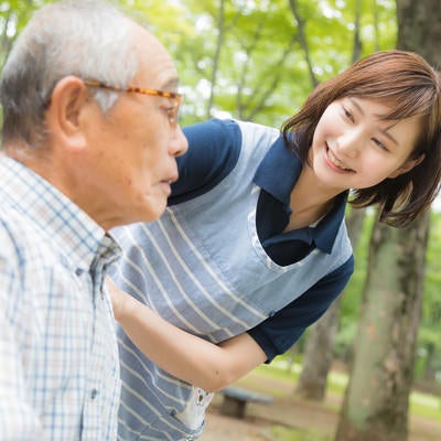 元気がないお爺さんに声をかける介護士の女性の写真