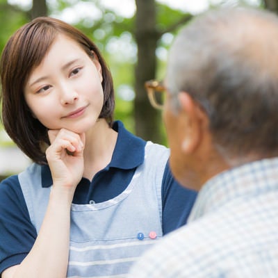 頑固な老人と対話する介護士の女性の写真