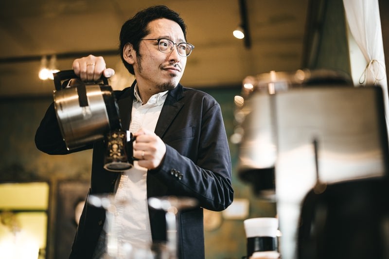 朝、出社後のコーヒーを飲む男性の写真