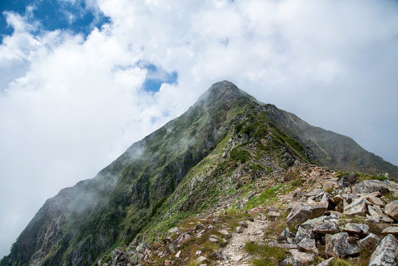 雲かかる山頂へと続く登山道の写真