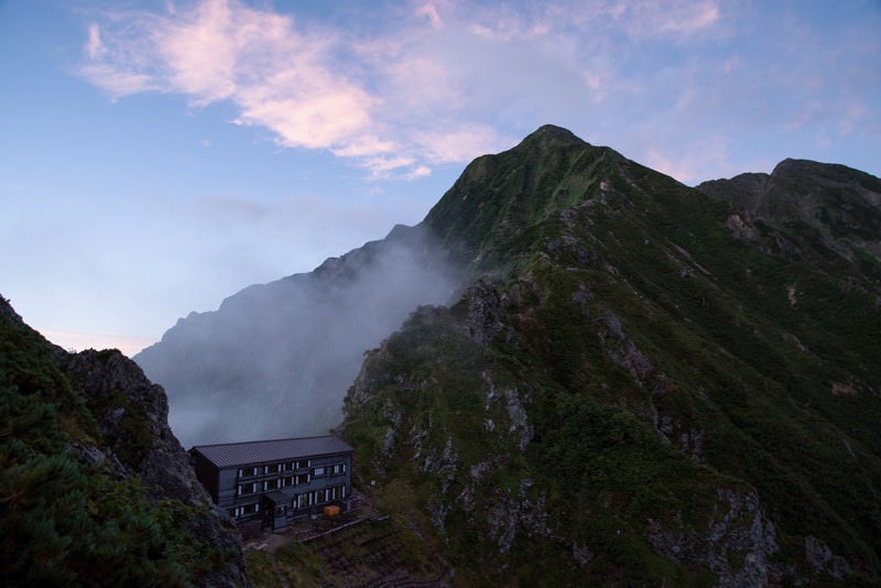 夕焼けに染まる稜線と山荘の写真