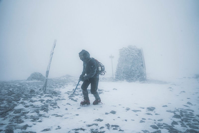 雪山の暴風に晒される登山者の写真