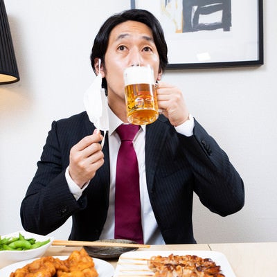 マスクをずらして生ビールを飲む会社員の写真