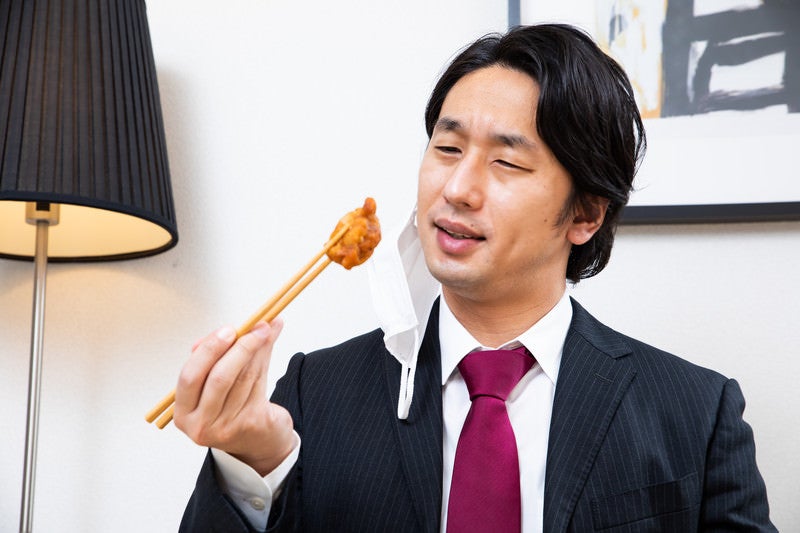 食べるごとにマスクを外す会社員の写真