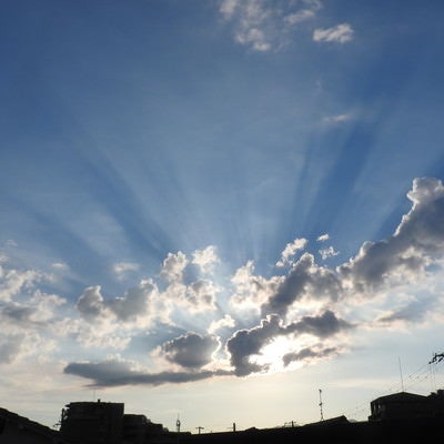 空にかかる夕陽の光芒の写真