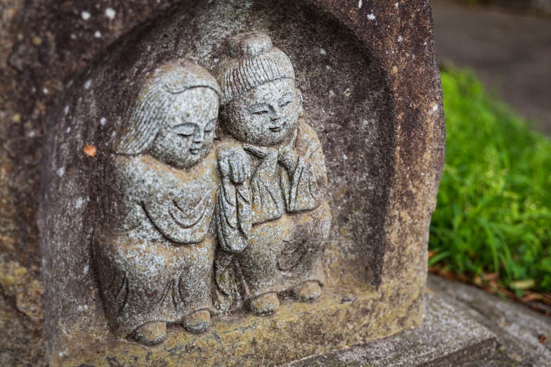 寄り添う姿の「双体道祖神」の石像の写真