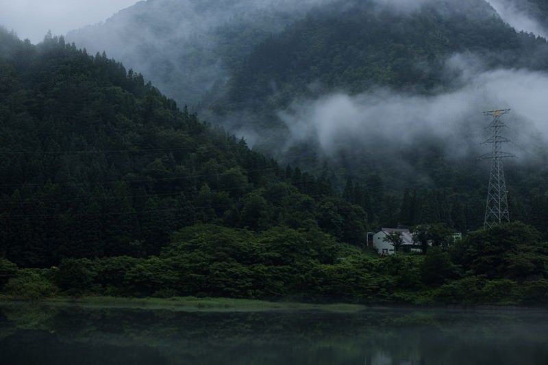 山から立ち上がる霧とダム湖の写真